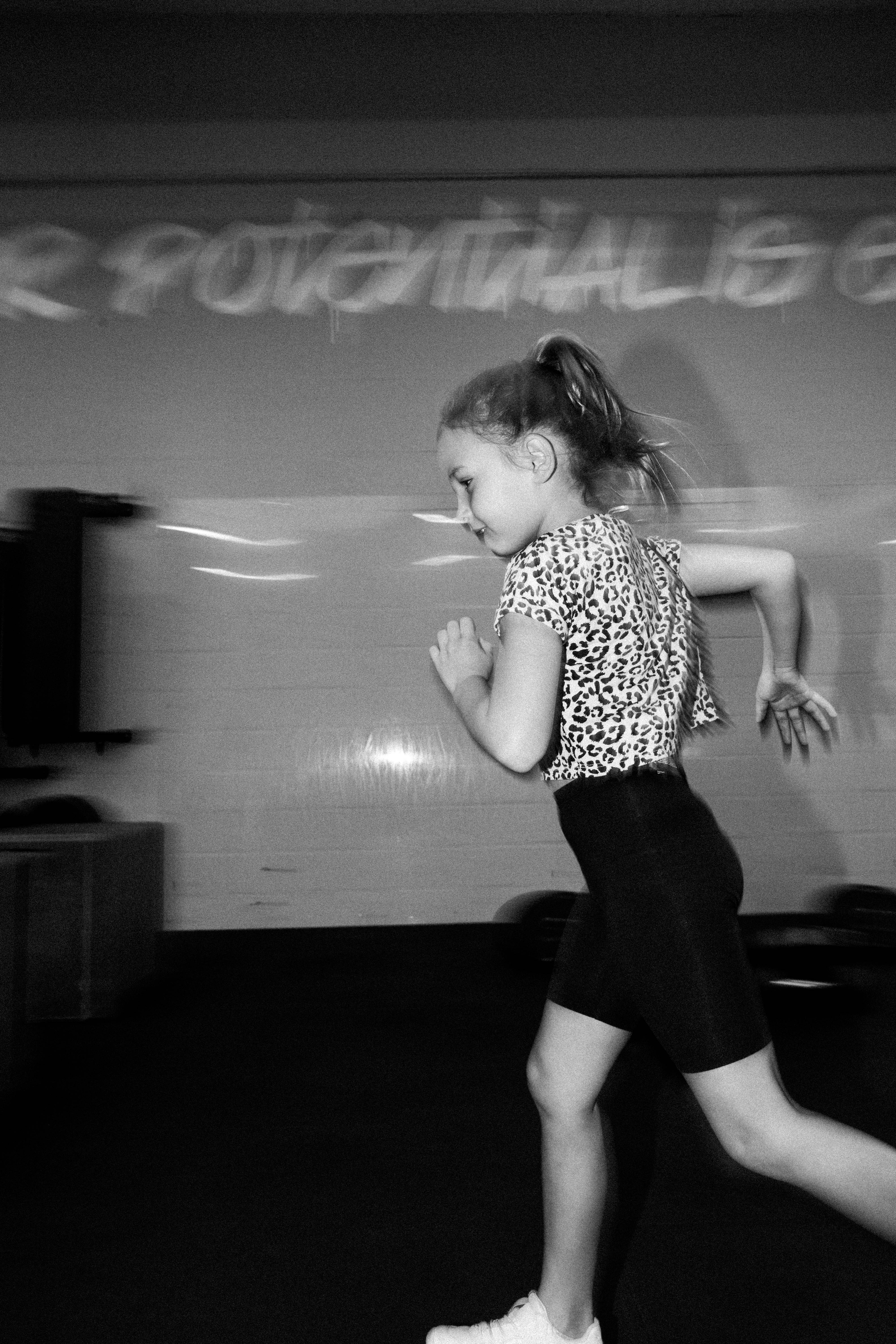Jeune fille en mouvement devant un mur peint de la salle